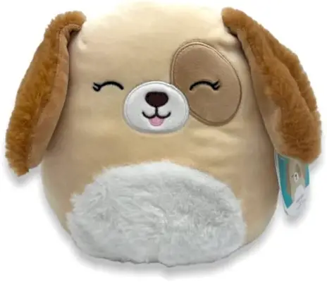 Um cachorro Squishmallow bronzeado com orelhas compridas e um tapa-olho, fazendo um bip