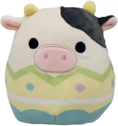 Una vaca blanca i negra Squishmallow amb una closca d'ou groc