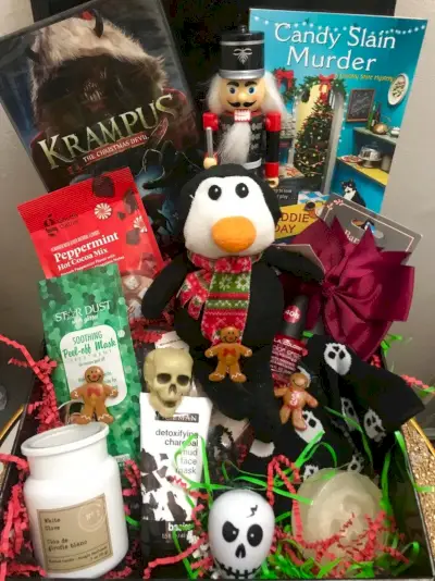 Une boîte remplie d'objets, dont un pingouin en peluche dans une écharpe de Noël, un petit crâne, un casse-noix effrayant et un film de Krampus.