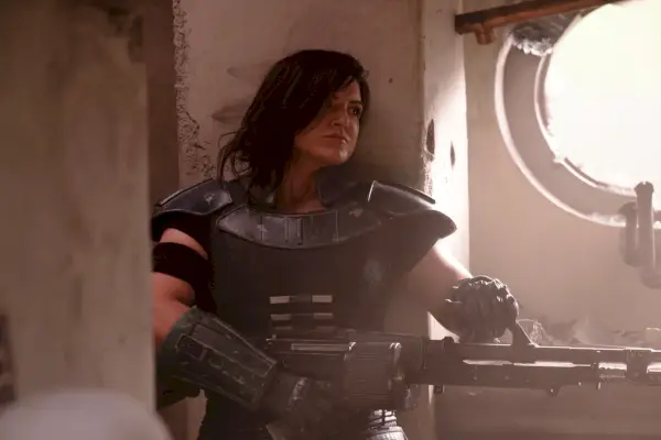 Gina Carano som Cara Dune i en kampscene i The Mandalorian, går gjennom en bygning, bevæpnet med en rifle