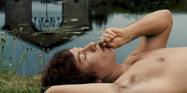 Oliver Quick (Barry Keoghan) fumando un cigarrillo junto al lago en