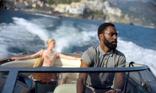 John David Washington bestuurt een motorboot terwijl een blonde vrouw op het achterschip in Tenet zit