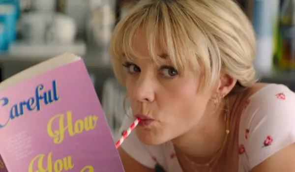 Carey Mulligan en Mujer joven prometedora, leyendo un libro y bebiendo de una pajita.