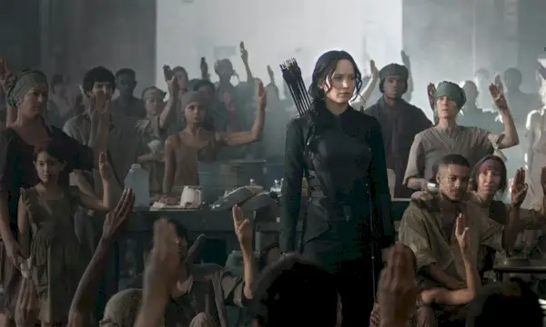 Afbeelding van District 8 uit de Hunger Games Mockingjay; Jennifer Lawrence als Katniss staat in een kamer met arme kledingarbeiders.