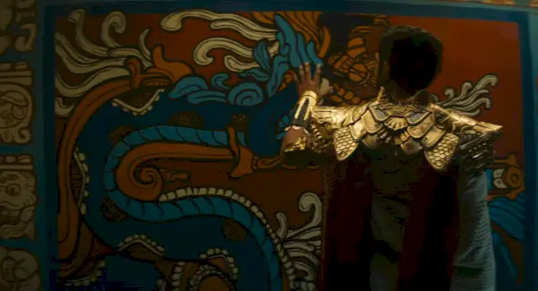 Captură de ecran din Black Panther: Wakanda Forever, care îl arată probabil pe Namor uitându-se la un perete în stil aztec. Imagine: Marvel Entertainment.