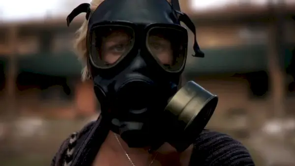 Whitney Able, met een gasmasker op, binnen