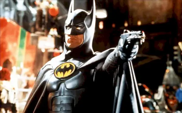 Michael Keaton som Bruce Wayne poserar med en pistol riktad mot någon in