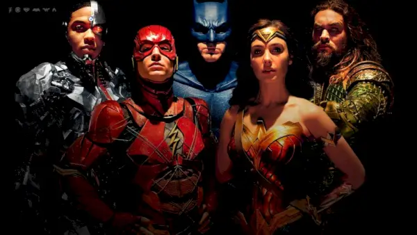 Die Justice League posiert gemeinsam vor einem schwarzen Hintergrund mit Blick auf den Bildschirm.