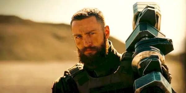 Aaron Taylor-Johnson como Ives sosteniendo un arma en Tenet