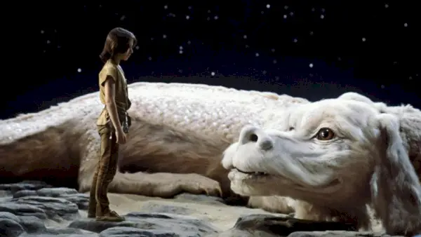 Et stillbillede fra filmen The NeverEnding Story, der skildrer Noah Hathaway som Atreyu, der står foran lykkens dragen Falkor under en stjernehimmel