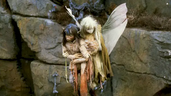 Et stillbillede fra filmen The Dark Crystal, der skildrer Gelflings Jen og Kira, der flyver op ad siden af ​​en klippeflade