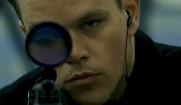 Matt Damon jako Jason Bourne patrzący przez karabin