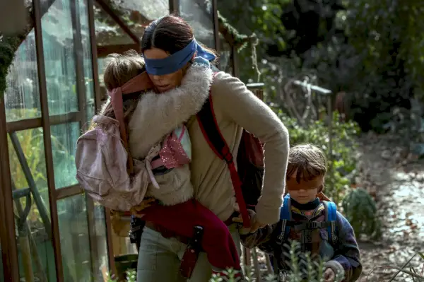 una donna bendata (Sandra Bullock) corre portando e trascinando con sé due bambini bendati