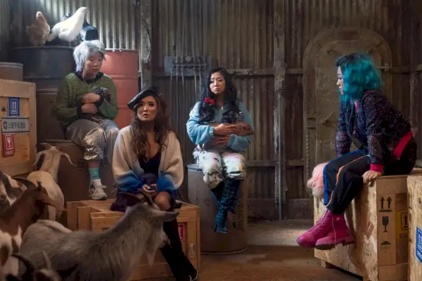 Les filles assises dans un hangar entourées d'animaux de la ferme dans Joy Ride