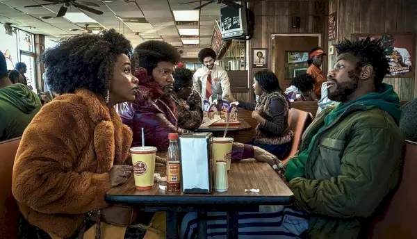 John Boyega, Teyonah Parris et Jamie Foxx sont assis à une table dans They Cloned Tyrone