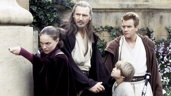 Prikazano slijeva: Natalie Portman (kao kraljica Padmé Amidala), Liam Neeson (kao Qui-Gon Jinn), Jake Lloyd (kao Anakin Skywalker), Ewan McGregor (kao Obi-Wan Kenobi) svi stoje zajedno.