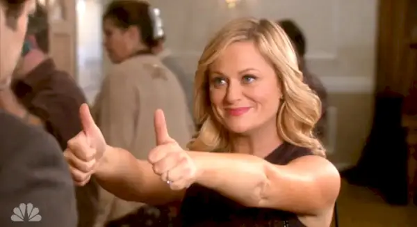 Amy Poehler se usmívá a dává dva palce nahoru jako Leslie Knope v Parks and Recreation.