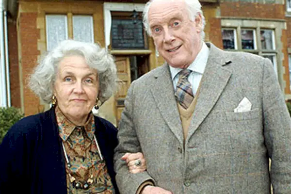 Imagen promocional de Esperando a Dios; Stephanie Cole, una anciana blanca de pelo blanco, junto a Graham Crowden, un anciano blanco.