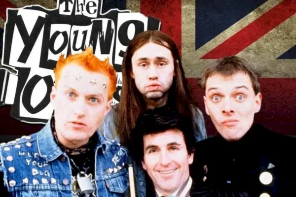 Image promotionnelle de The Young Ones ; Rik Mayall, Nigel Planer, Adrian Edmondson et Christopher Ryan, tous jeunes hommes blancs, se tiennent devant un Union Jack et le nom du spectacle en noir sur des carrés blancs.