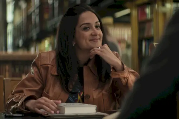 Nadia souriante à la bibliothèque dans You saison 4