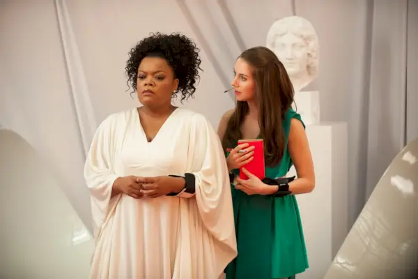 Encara de l'episodi Community Development and Condiments; Yvette Nicole Brown es troba amb les mans juntes amb un vestit grec amb màniga de cortines blanques, mentre que Alison Bree amb una túnica grega de ciència-ficció verda es troba darrere i a la dreta d'ella amb una mirada atenta.