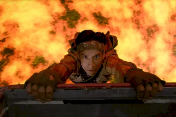 Ainda do episódio Community Escapismo Geotérmico; Danny Pudi, vestindo uniforme militar, balança sobre a lava.